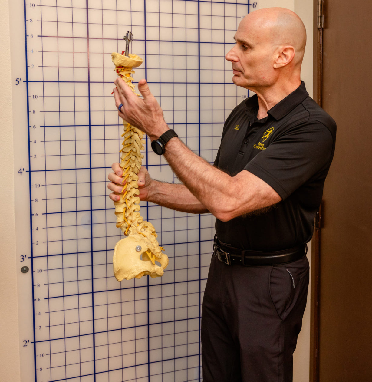 Man holding a spine model against a 'PostureZone' chart